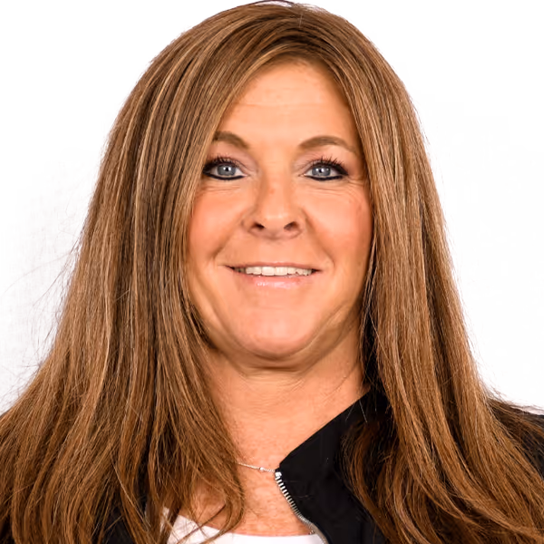 Smiling woman with long light brown hair wearing a black jacket over a white shirt.