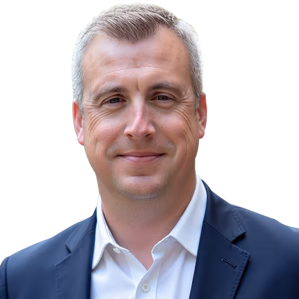Smiling man with short light brown hair wearing a white shirt and navy blazer.