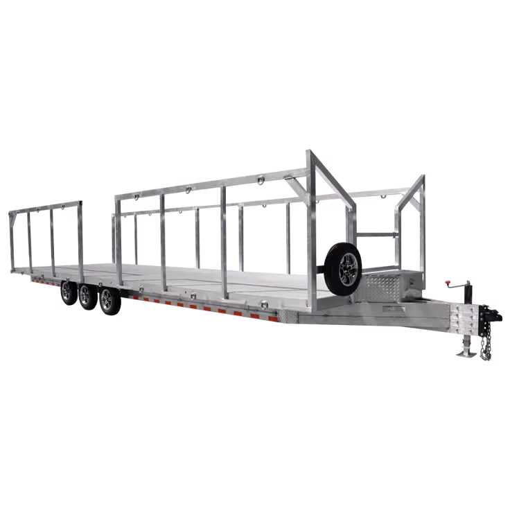 A long aluminum trailer with an open frame, three axles, and a spare tire attached to the side.
