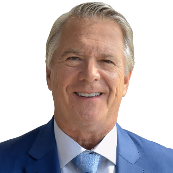 Smiling mature man with gray hair wearing a blue suit, white shirt, and light blue tie.