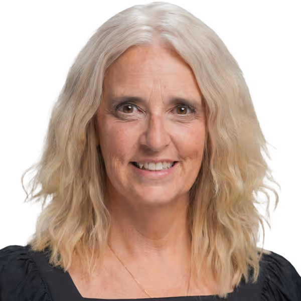 Smiling mature woman with shoulder-length wavy blonde hair wearing a black top.