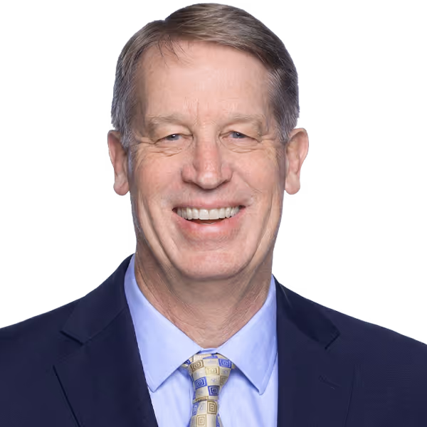 Middle-aged man with light brown hair wearing a suit and patterned tie, smiling at the camera.
