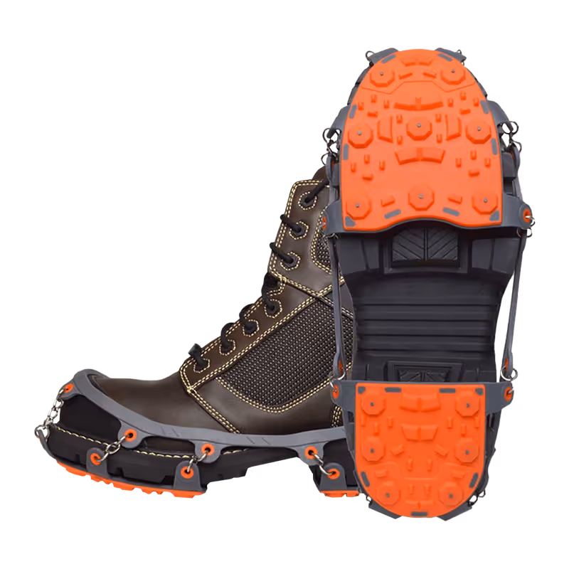 Brown boots with orange and black ice cleats attached to the soles for enhanced traction.