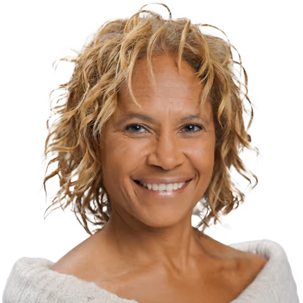 Smiling middle-aged woman with curly blonde hair wearing an off-shoulder sweater.