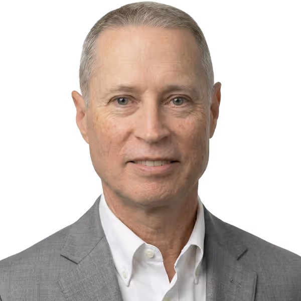 Middle-aged man with short gray hair wearing a gray blazer and white collared shirt smiling.