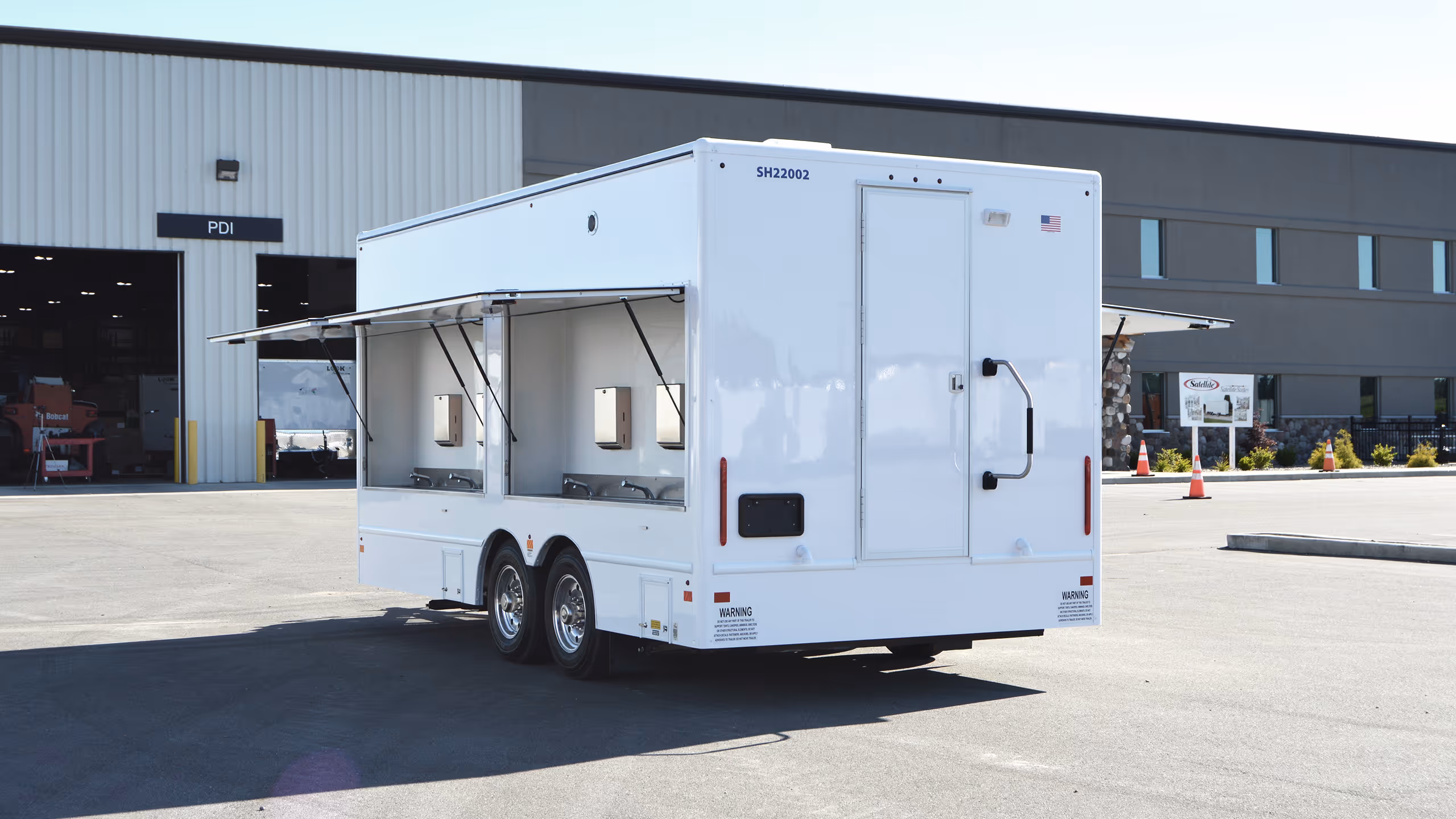 A white trailer with dual side windows parked outside a industrial building.