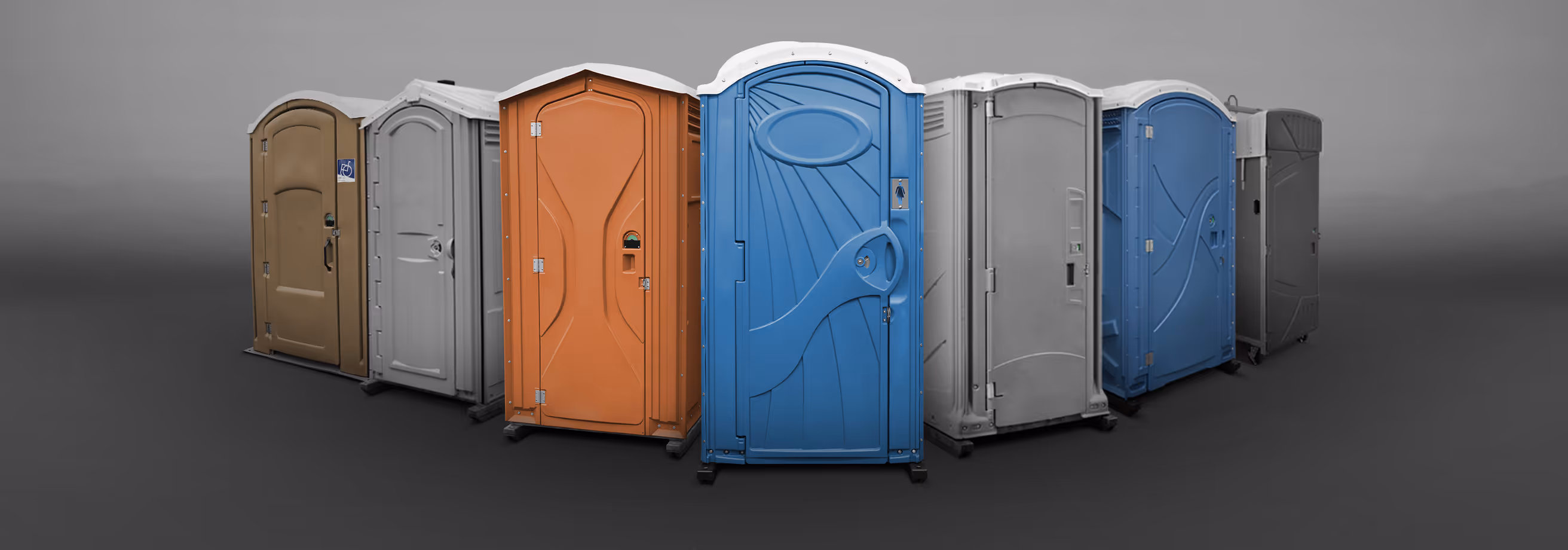 Various portable restrooms in different colors arranged in a semi-circle against a gray background.