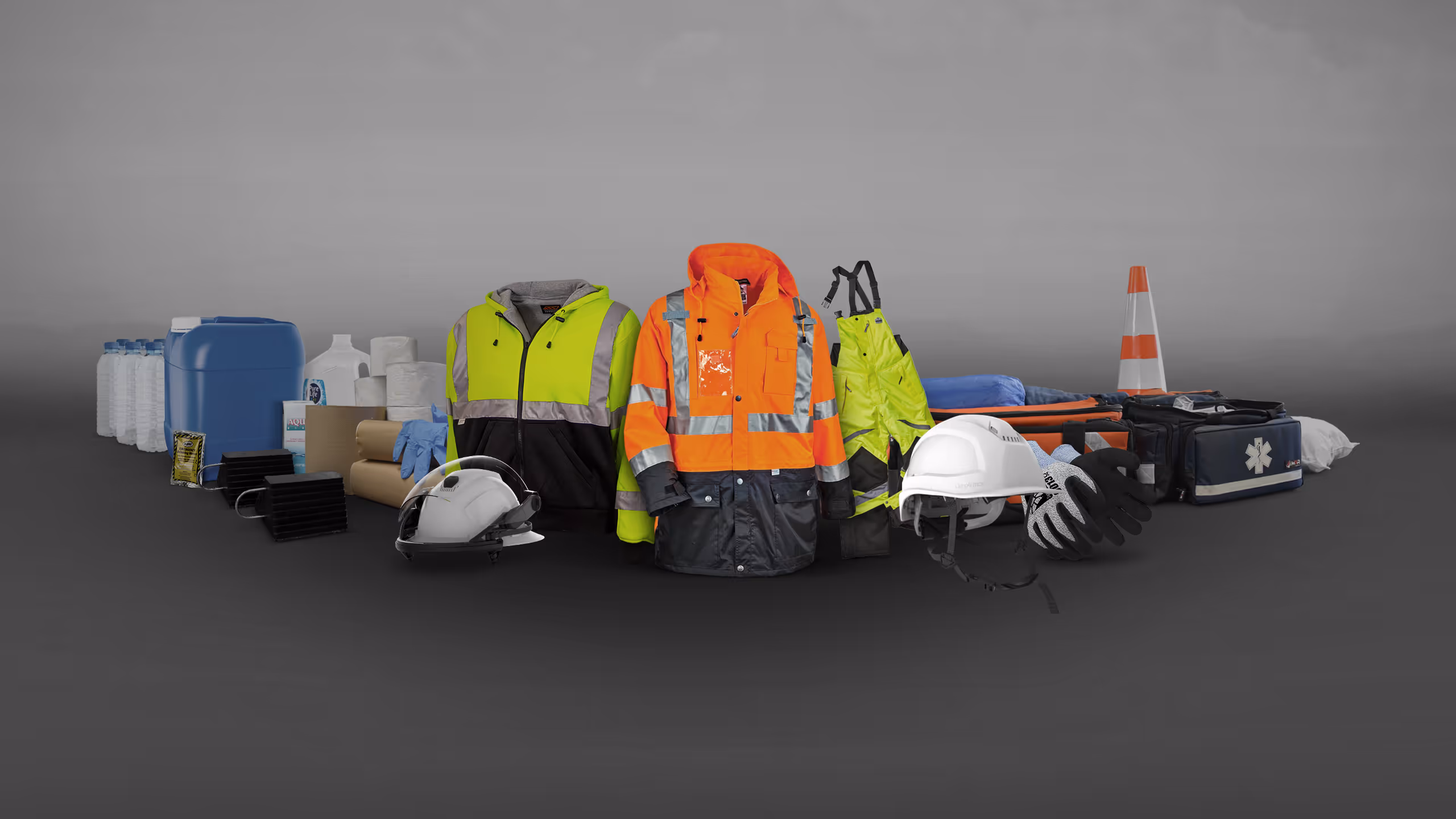 Safety gear and equipment arranged on a gray background, including jackets, helmets, cones, and