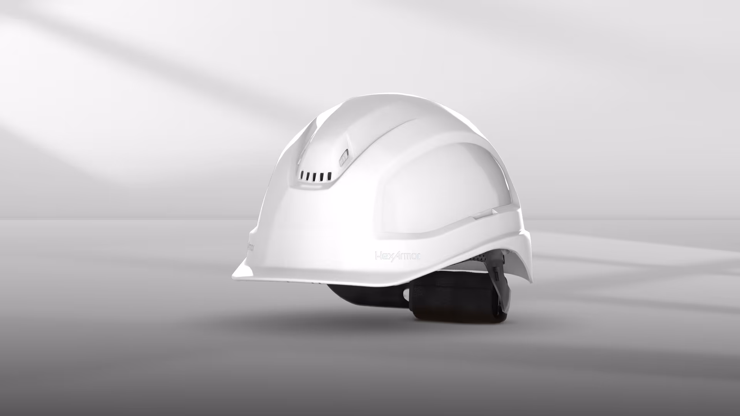 White hard hat positioned on a light gray surface with soft shadows.