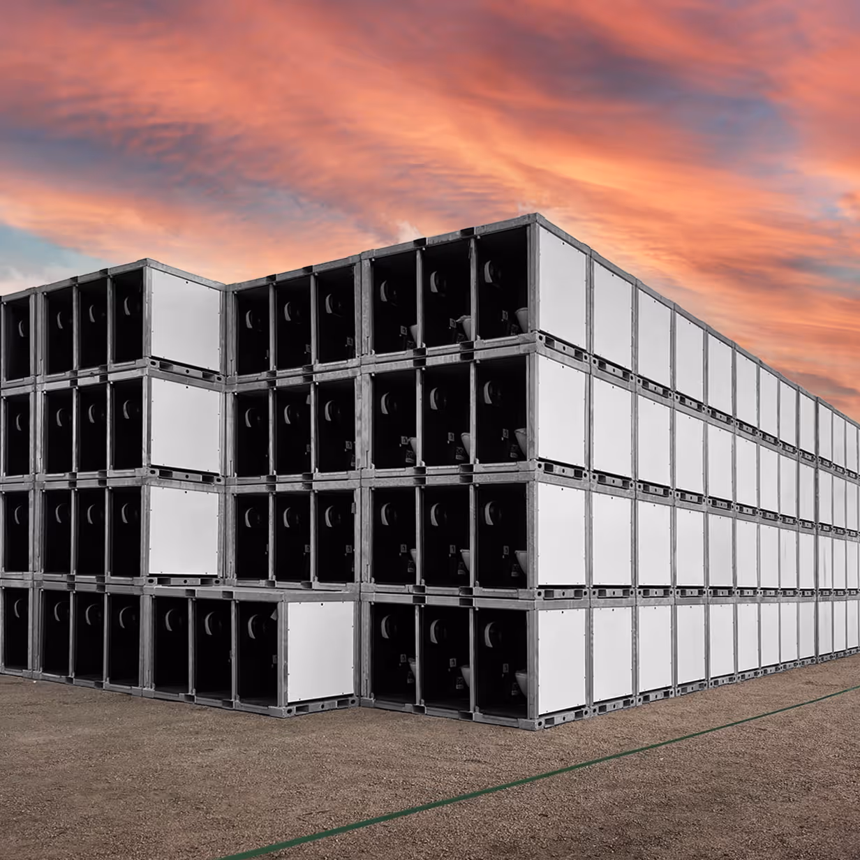 Stacked cargo containers outdoors under a colorful sunset sky on a dirt surface.