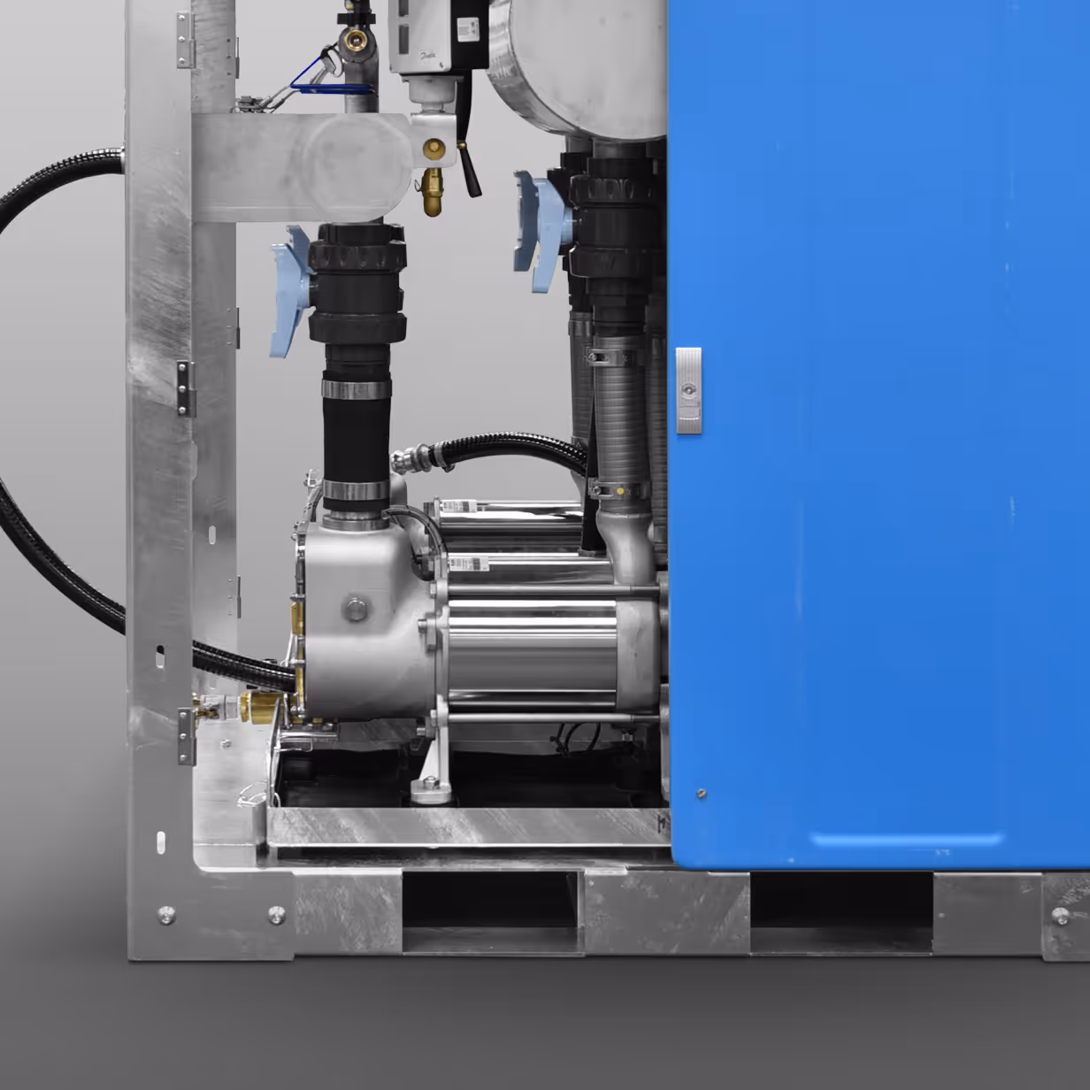 Close-up of industrial equipment with metal pipes, valves, and a blue control panel on a gray background.