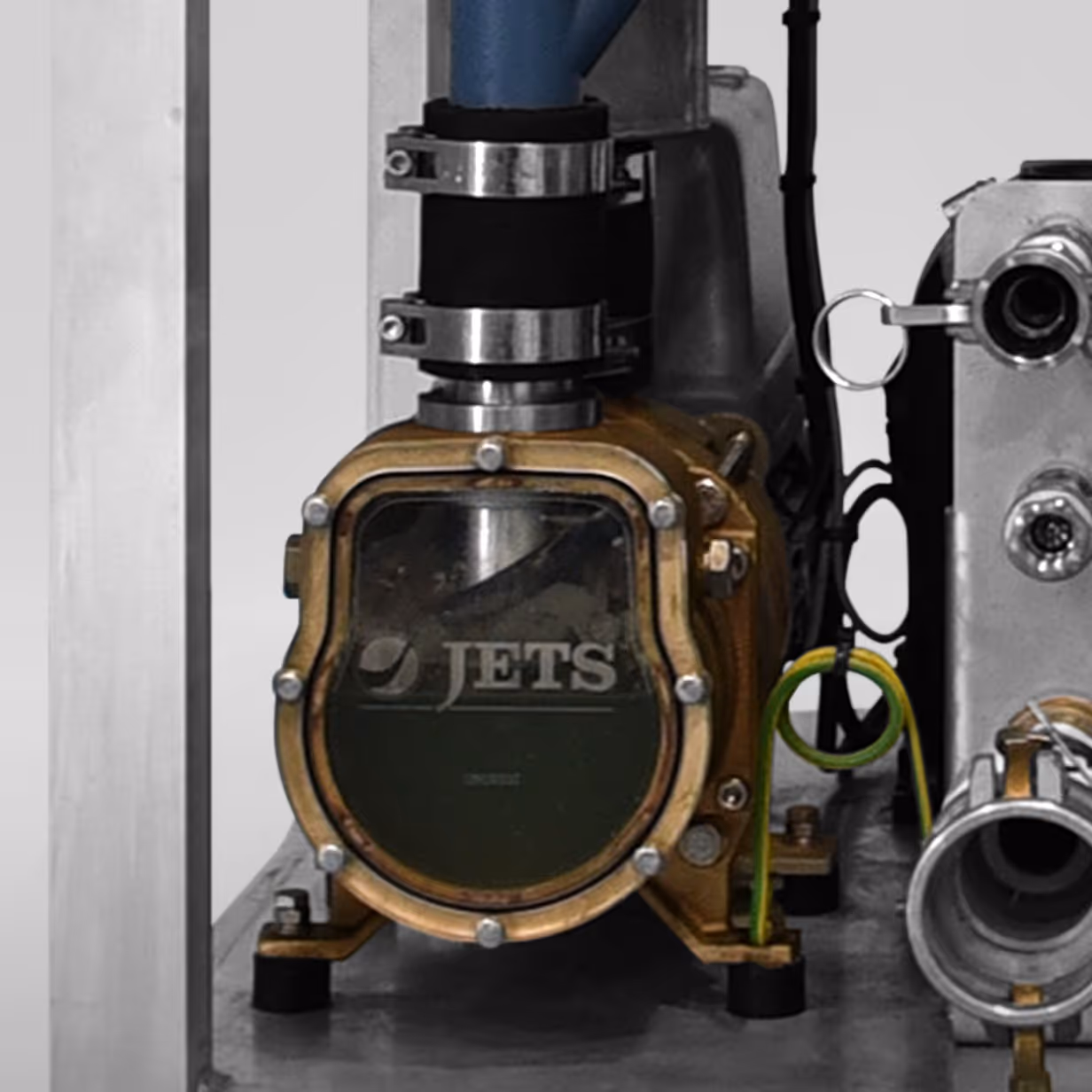 Close-up of a JETS branded industrial pump with metal fittings and green and yellow wire attached.