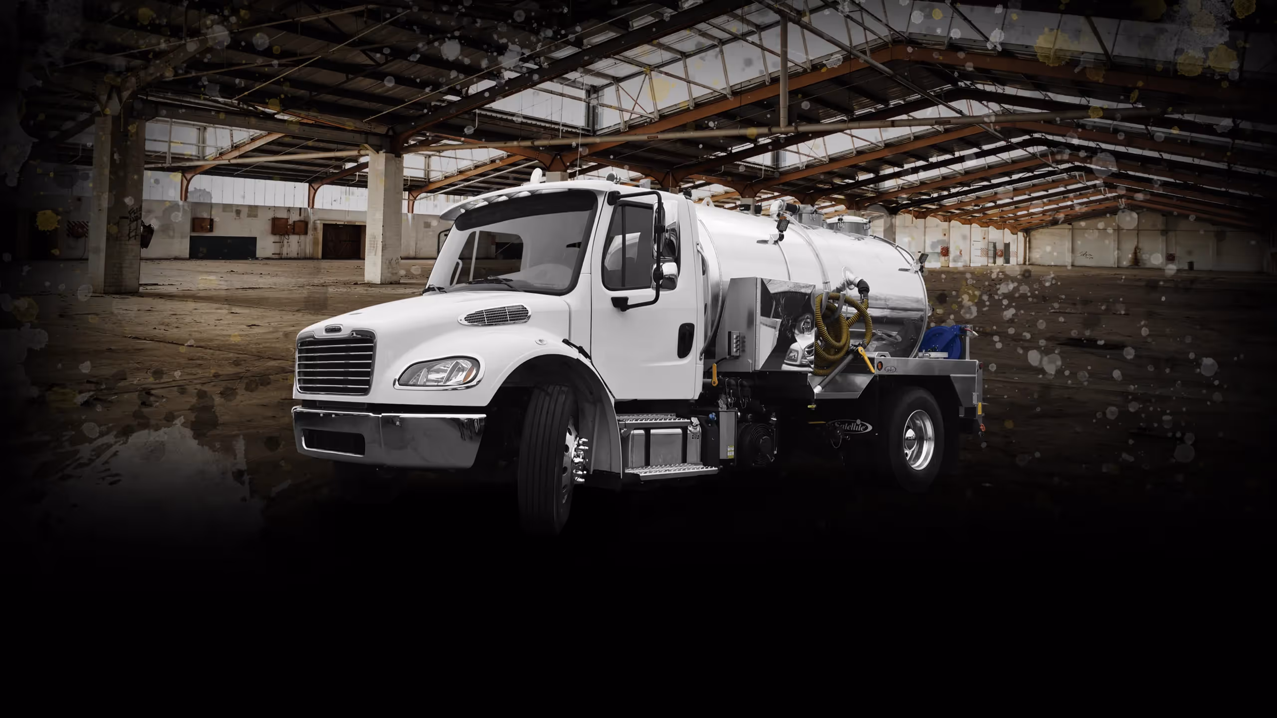 White industrial vacuum truck parked inside a large empty warehouse.