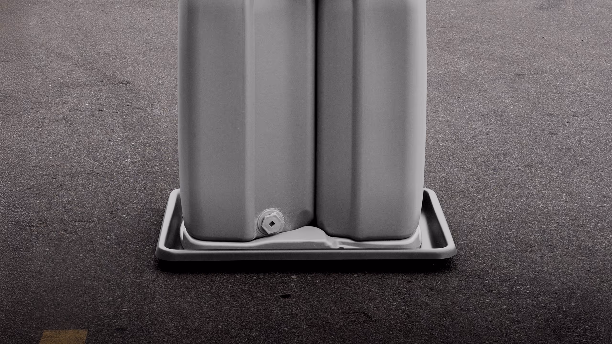 Close-up of two gray plastic containers on a rectangular tray on asphalt surface.