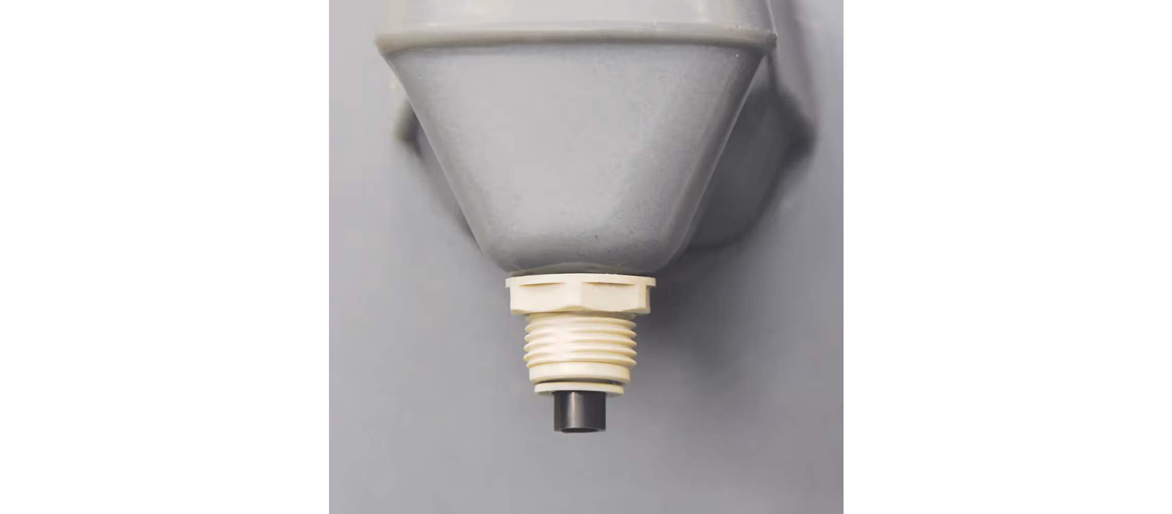 Gray funnel with a threaded neck and a small nozzle at the bottom, mounted on a wall.