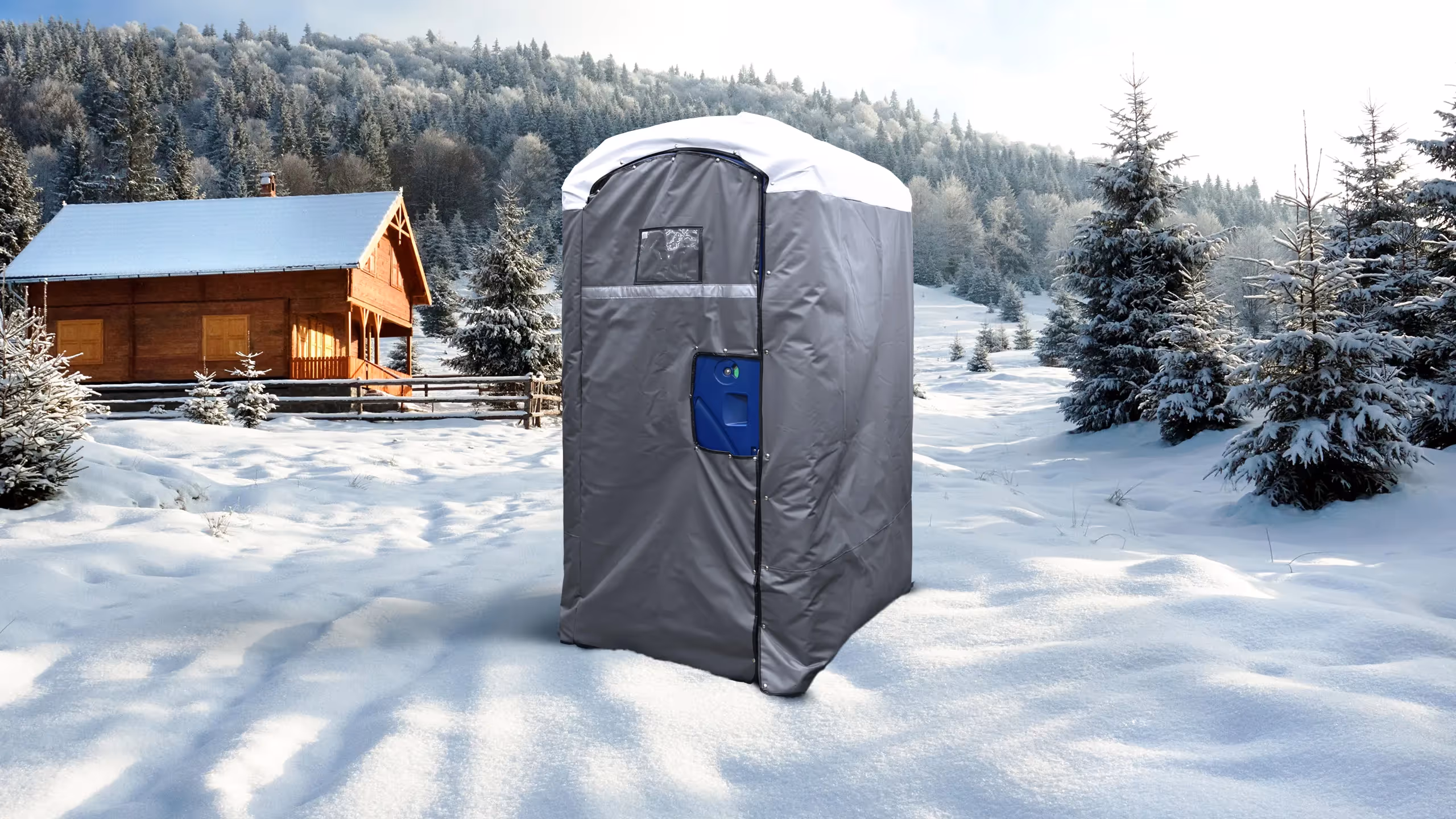 A gray insulated portable restroom cover in a snowy landscape near a wooden cabin and pine trees.
