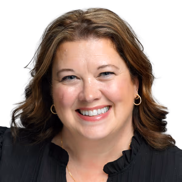 Smiling woman with shoulder-length brown hair wearing gold hoop earrings and a black top.