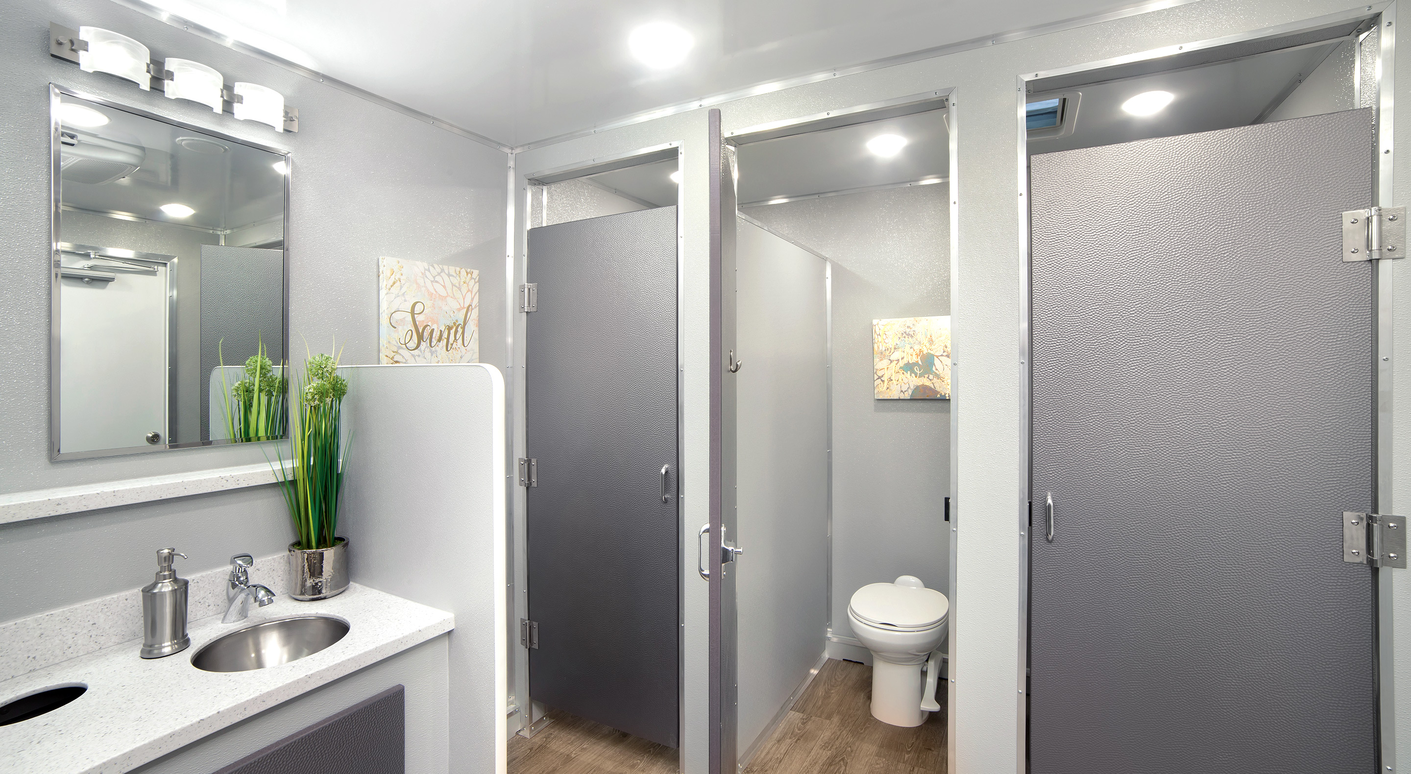Modern restroom interior featuring three stalls, a sink, and decorative wall accents.
