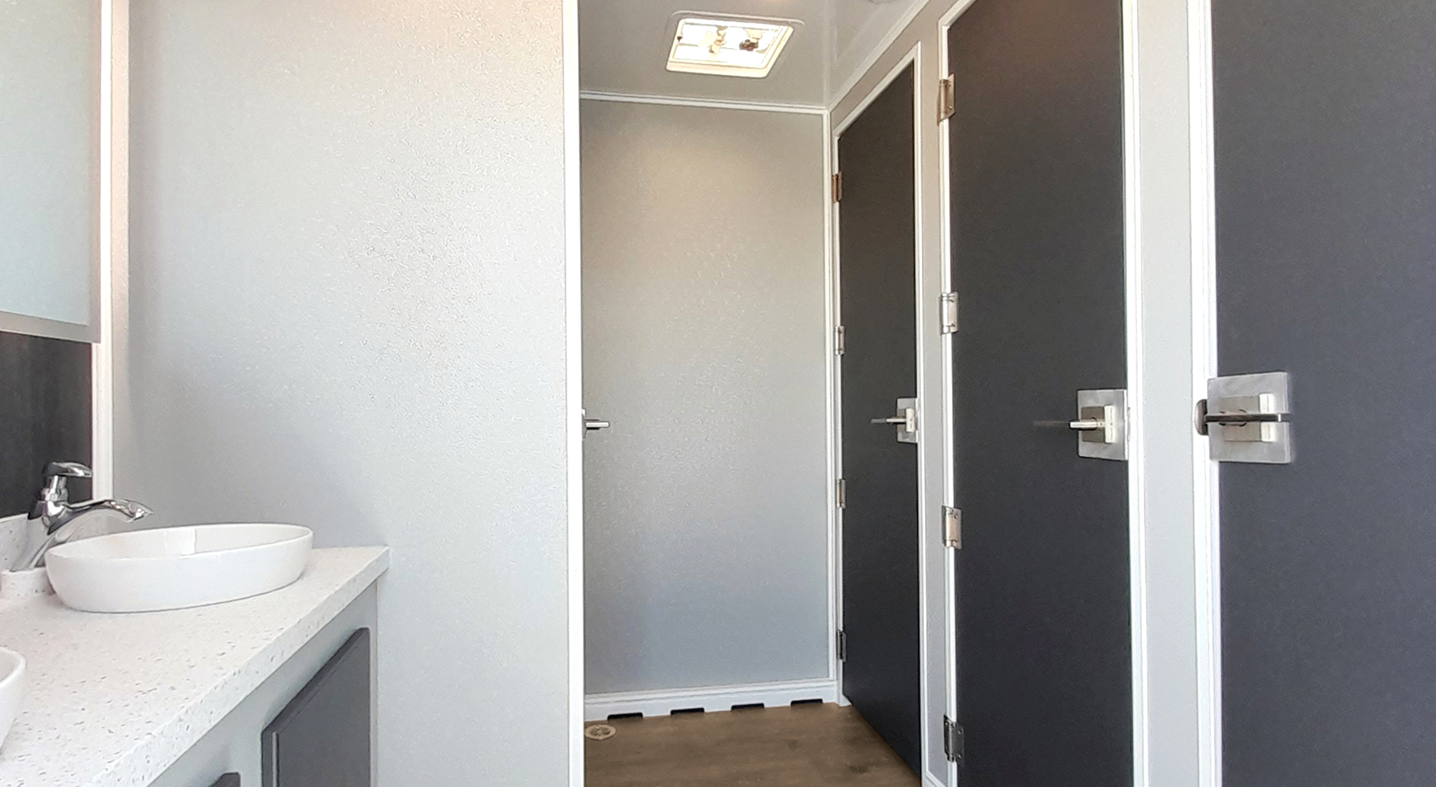 Clean and modern restroom with three stall doors and a sleek sink area.