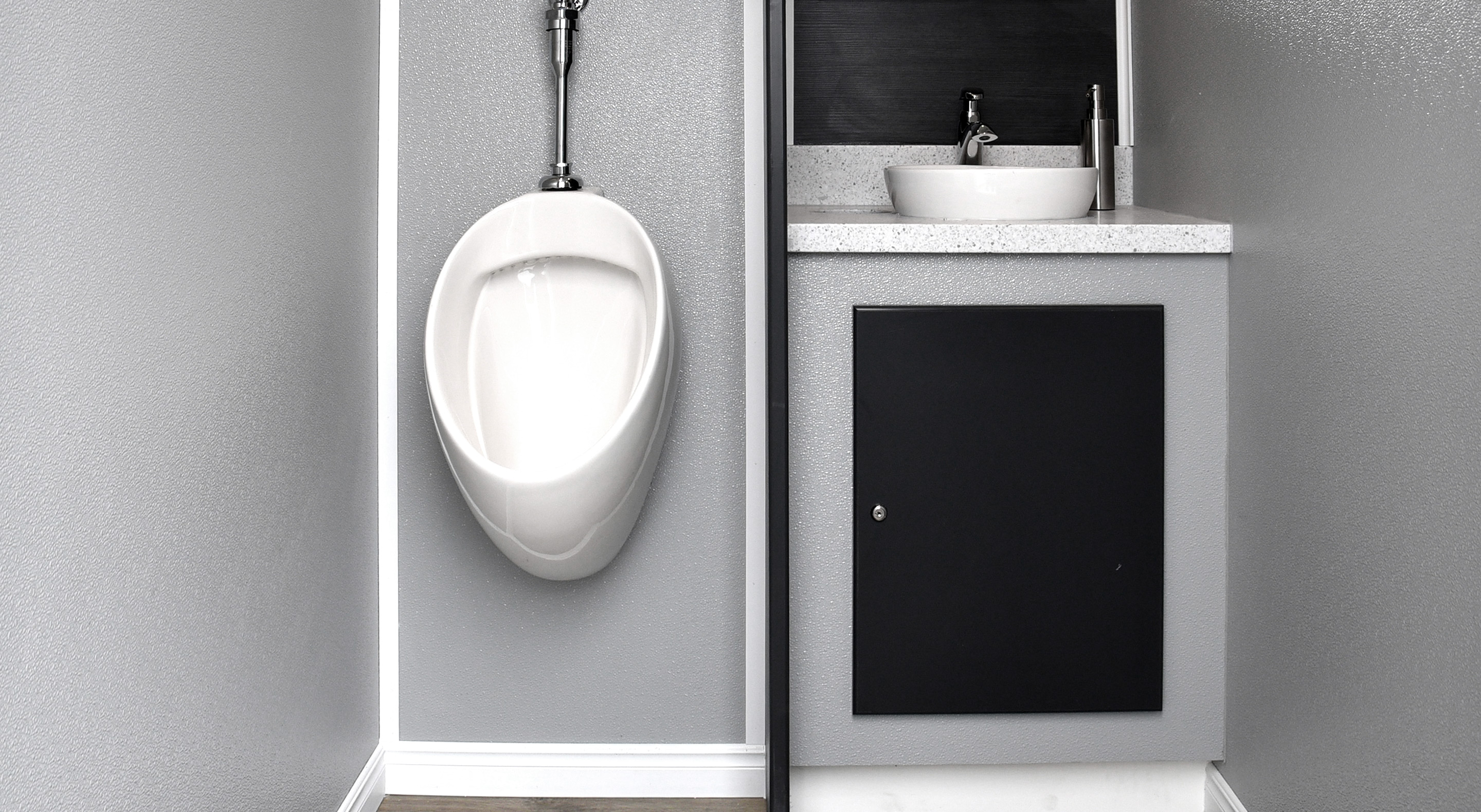 Modern bathroom corner with a white wall-mounted urinal and a gray cabinet with vessel sink.