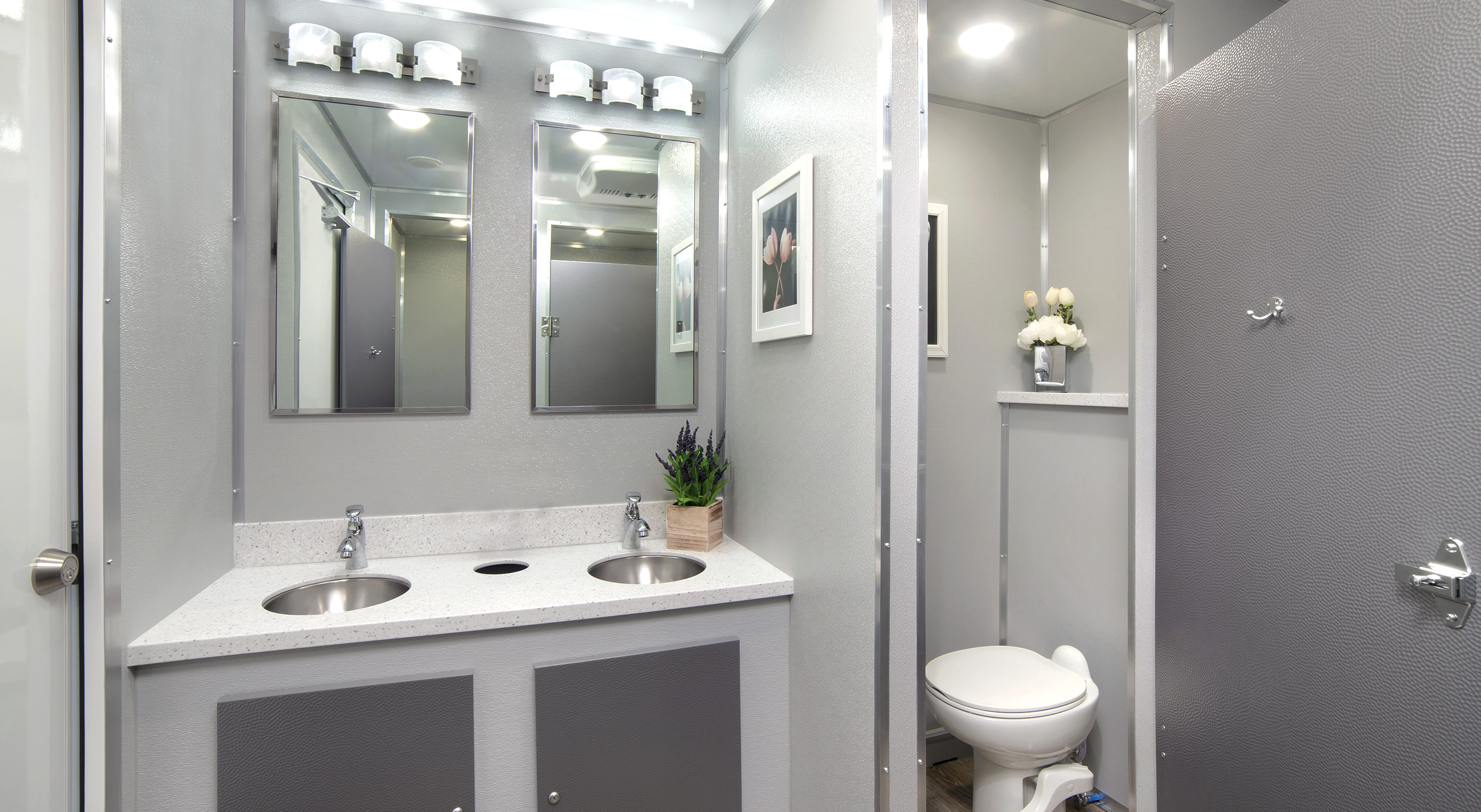 Modern commercial bathroom with dual sinks, mirrors, and a toilet in a sleek, gray design.