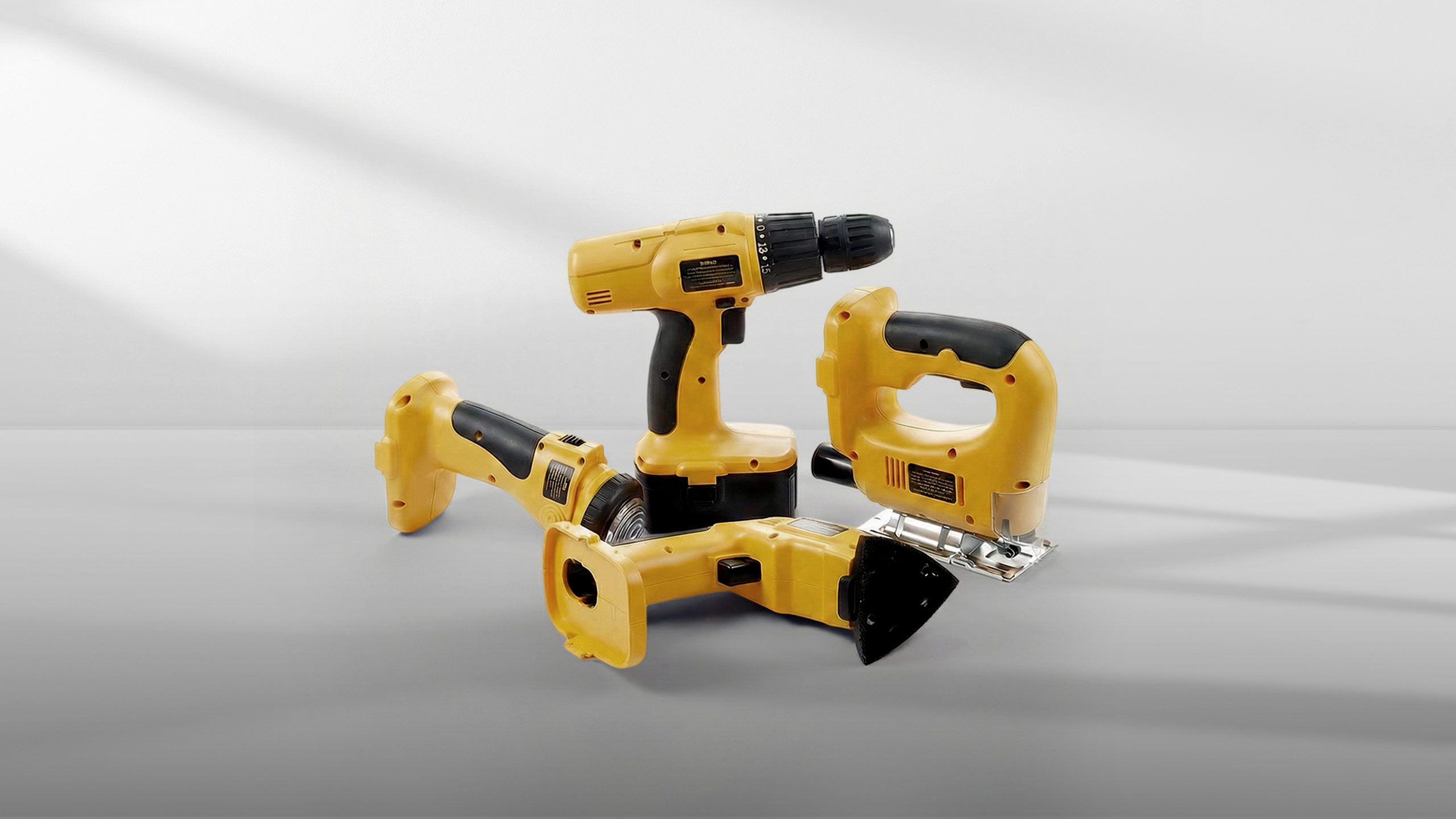 Three yellow and black cordless power tools on a gray surface with a white background.