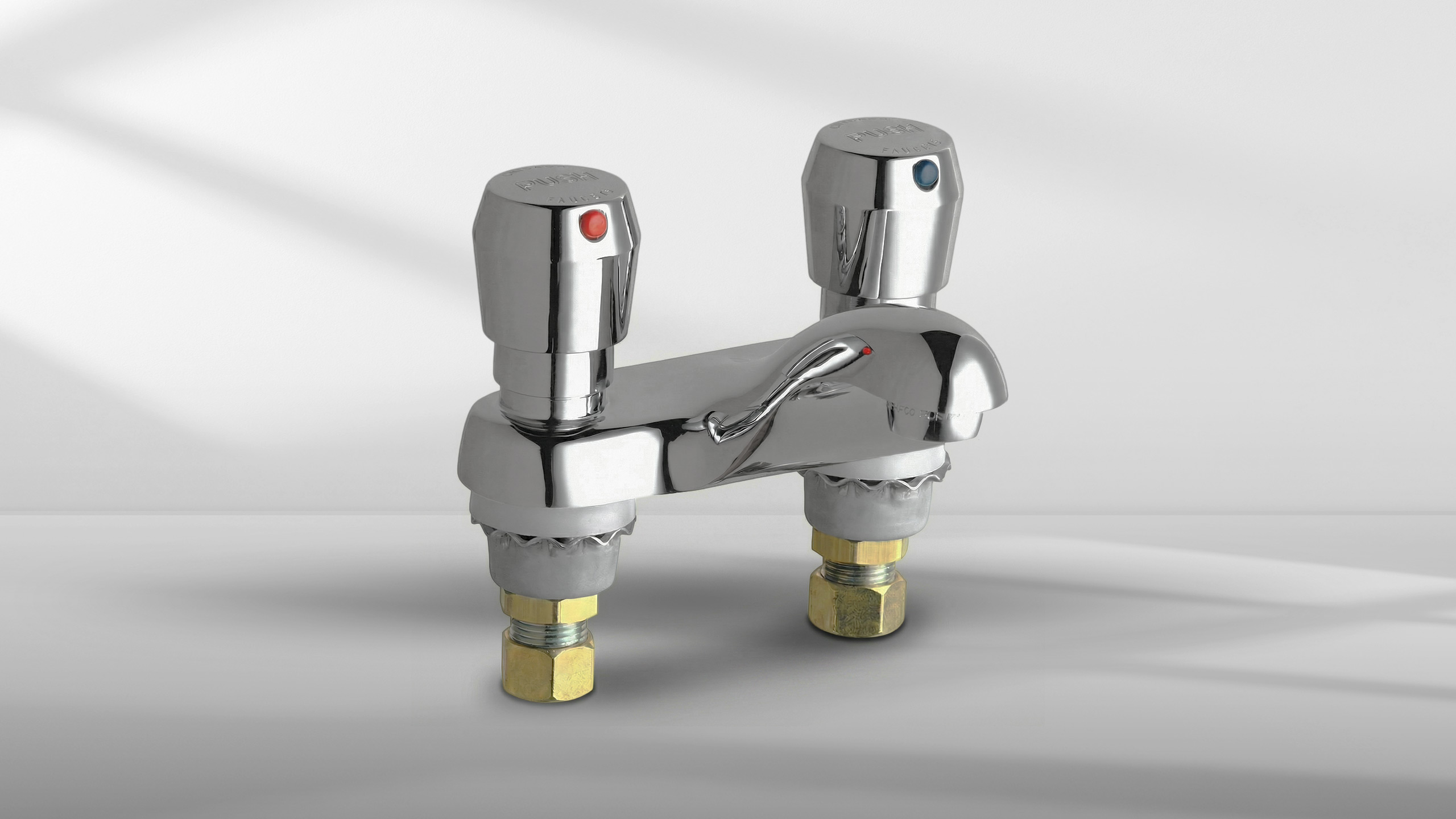 Chrome faucet with separate red and blue push handles for hot and cold water on white surface.
