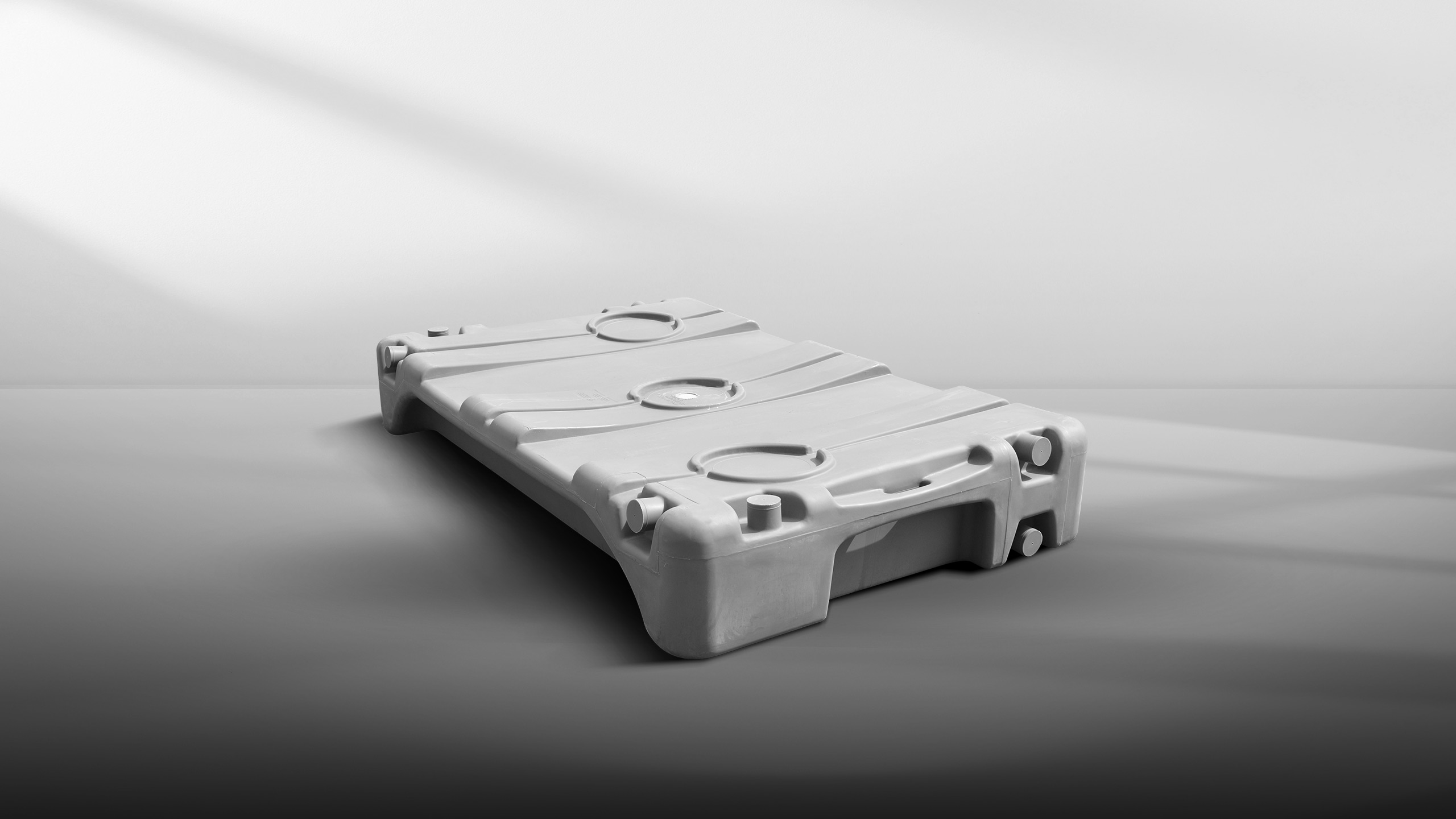 Large rectangular gray plastic holding tank with circular openings on top, in a minimalist setting.