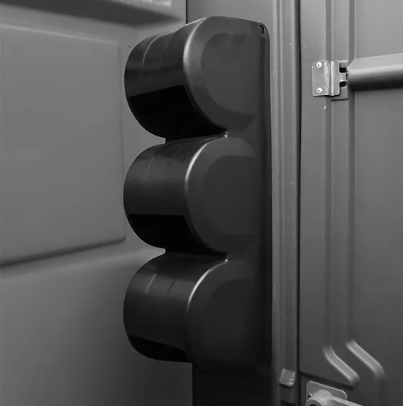 Black triple-cylinder lock on the corner edge of a door or panel in grayscale.