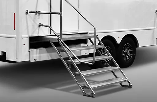 Metal stairs leading to the entrance of a white trailer with black wheels on a gray floor.