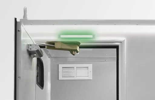 Part of a metal door frame with a green emergency exit light above it.