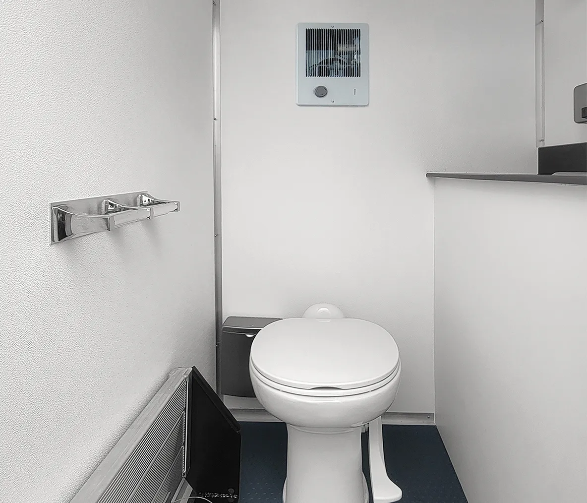 Minimalist white toilet in a small bathroom with a wall heater and a vent above it.