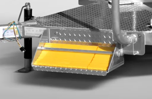 Close-up of a metal trailer component with a yellow reflective panel attached below a diamond plate surface.