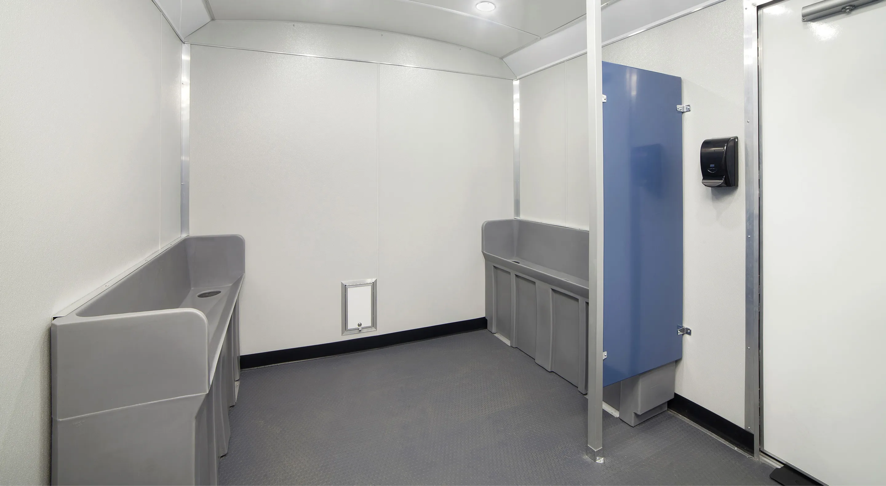 Spacious restroom with two wall-mounted gray sinks, white walls, blue stall door, and black paper towel dispenser.