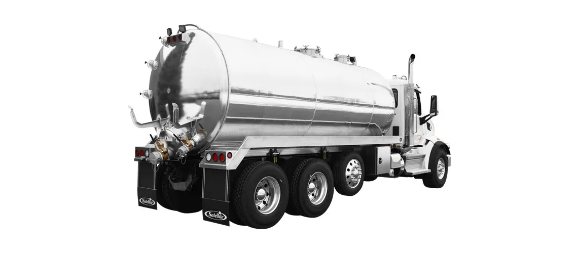 White tanker truck with shiny cylindrical metal tank viewed from rear side on white background.