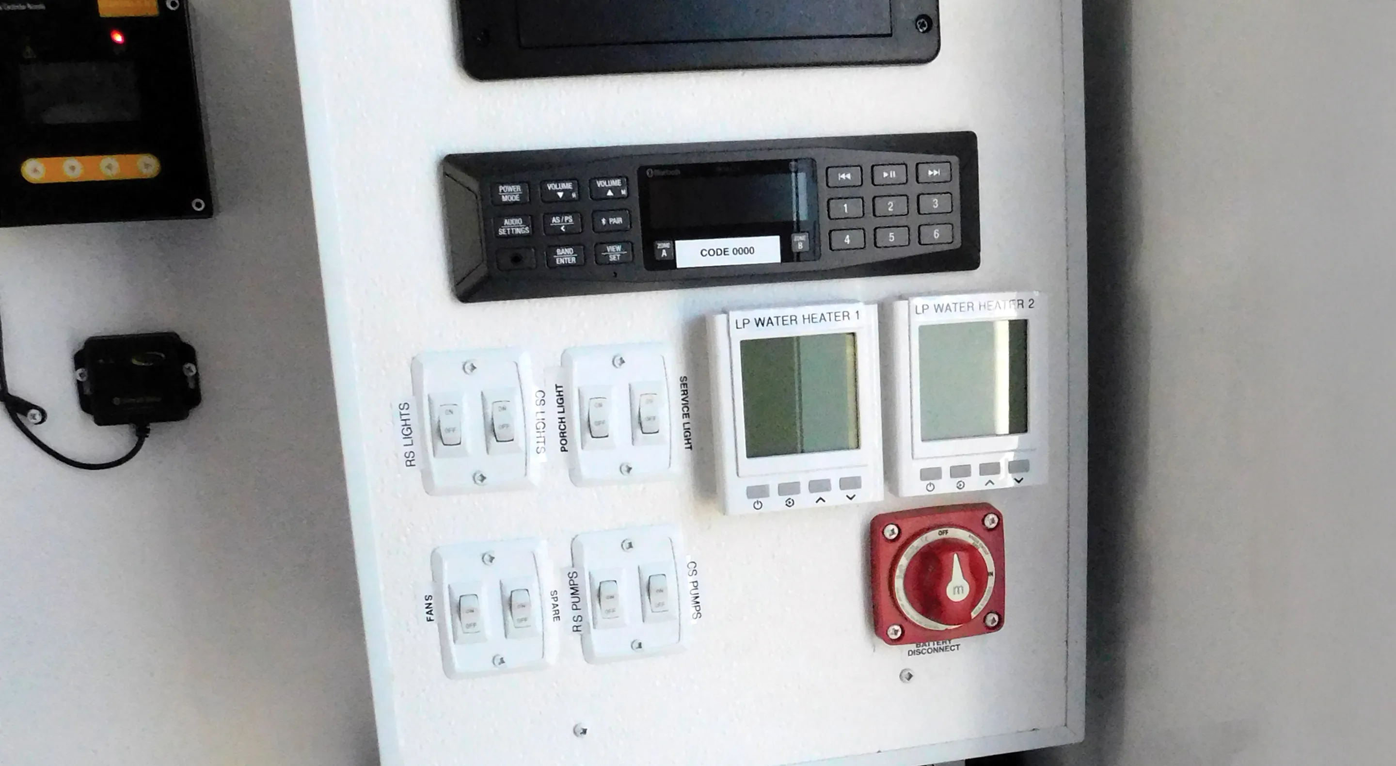 Control panel with switches for lights, pumps, two LP water heater displays, and a red battery disconnect switch.